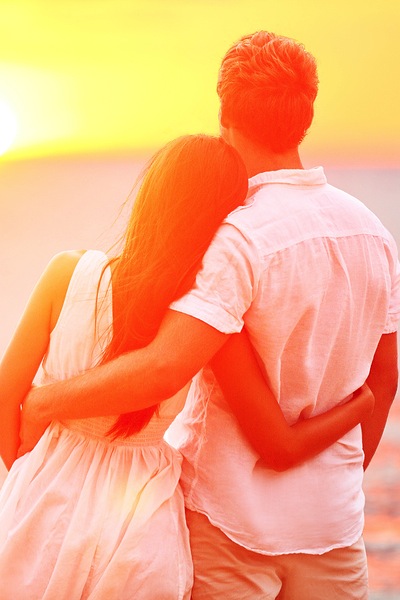 Honeymoon couple romantic in love at beach sunset. Newlywed happy young couple embracing enjoying oc