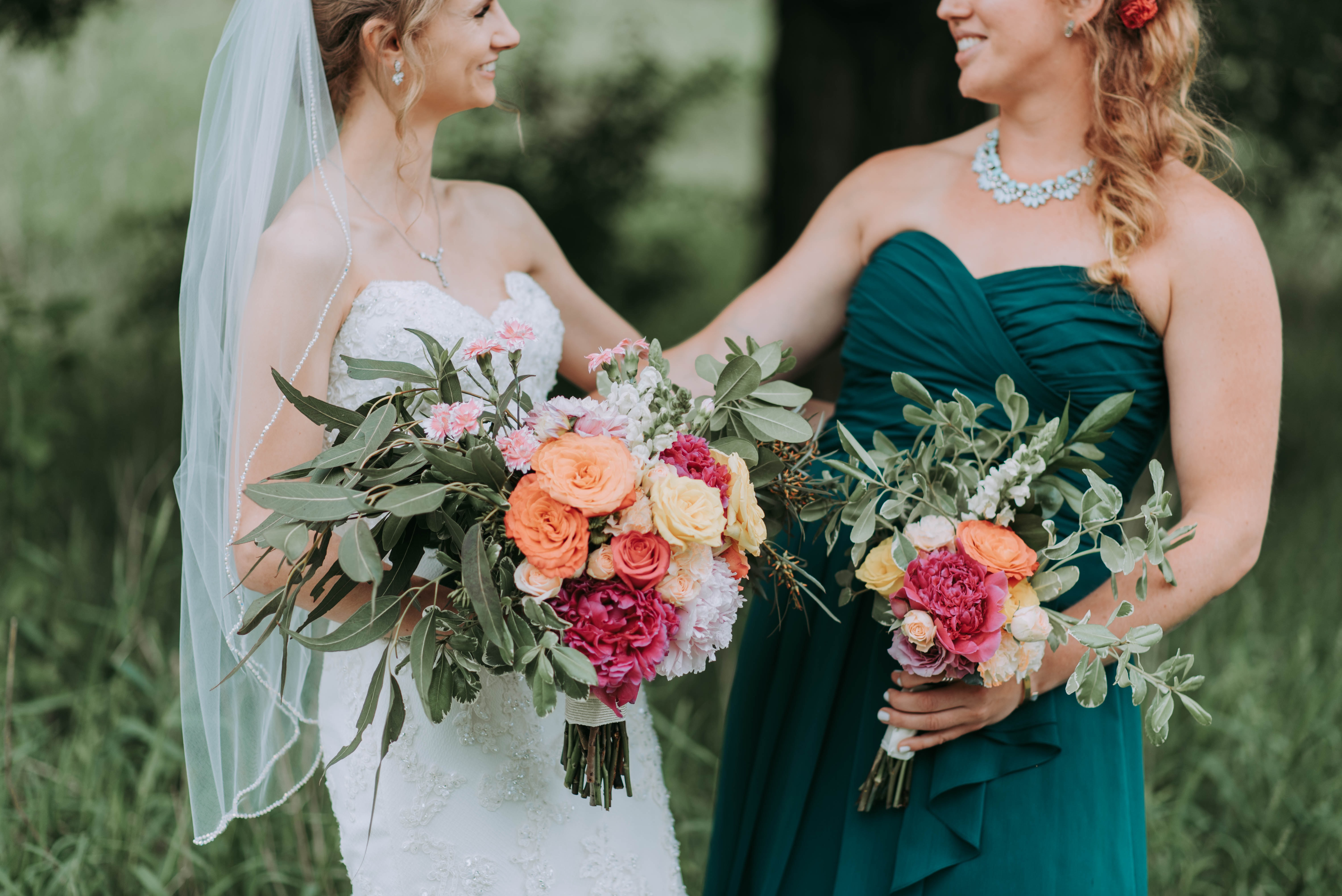 A bride smiling with her bridesmaid in green